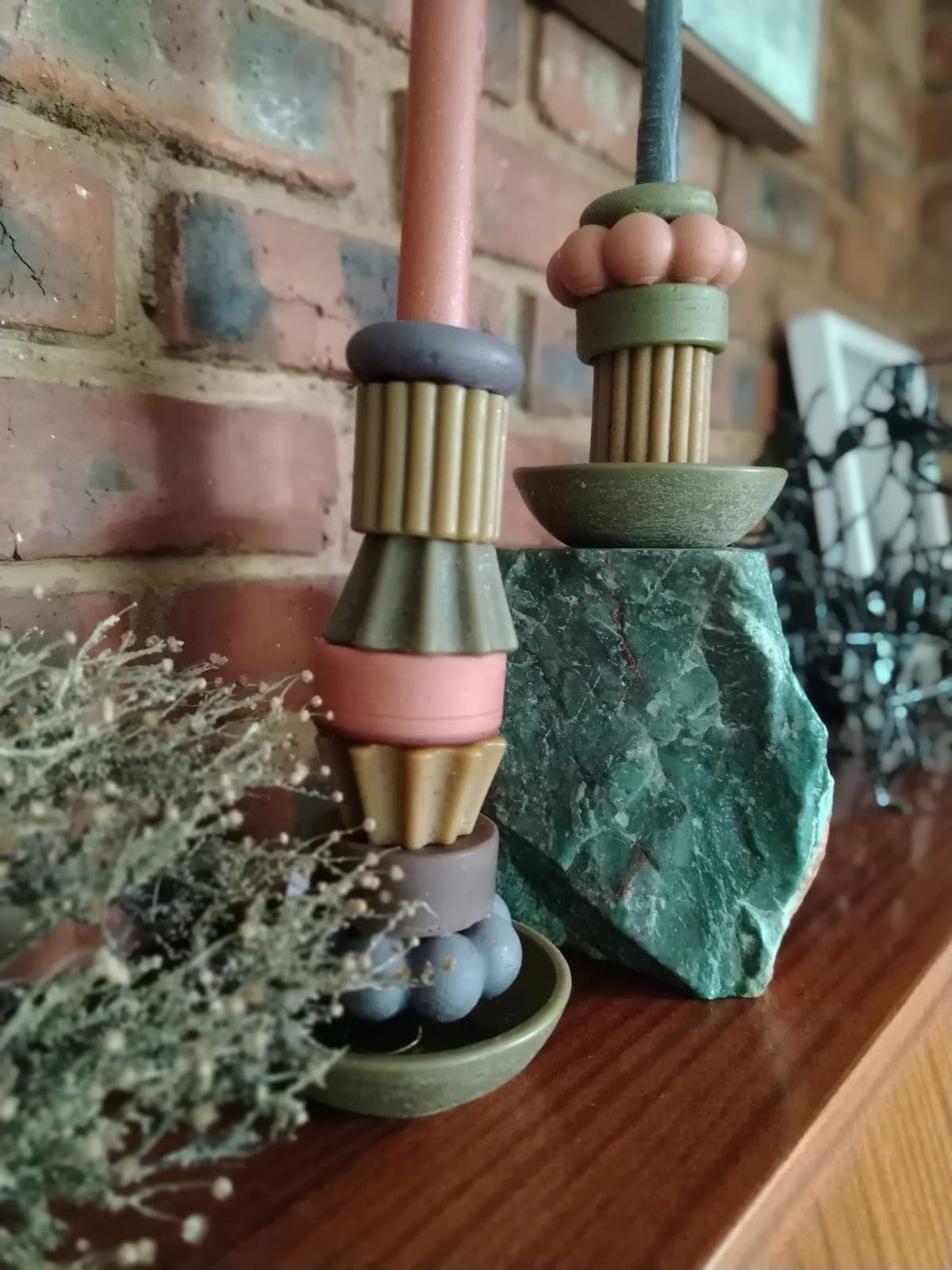 Earthy toned candles on mantelpiece with dried flowers